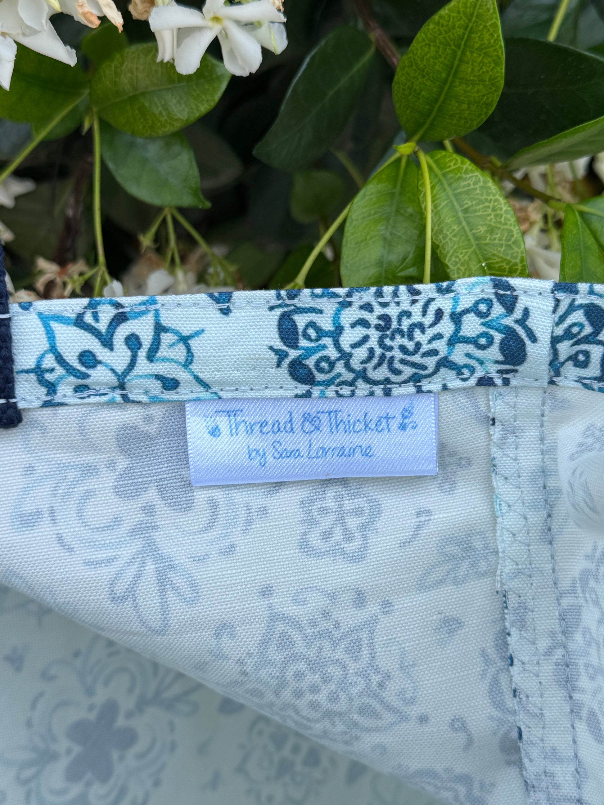Artistic floral reusable tote bag close up fabric tag detail in blue