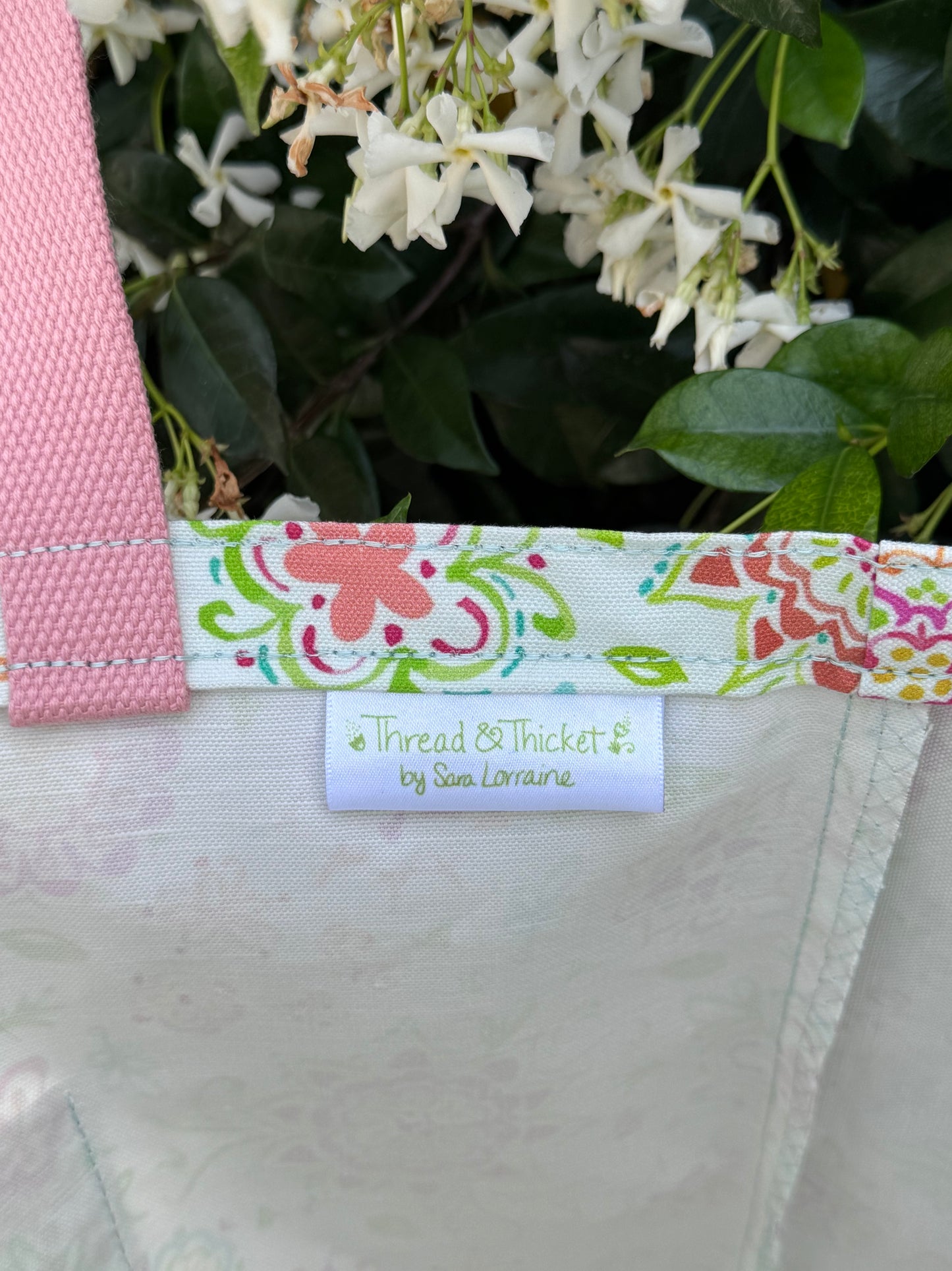 Hand painted floral watercolor reusable tote bag close up fabric tag detail in green